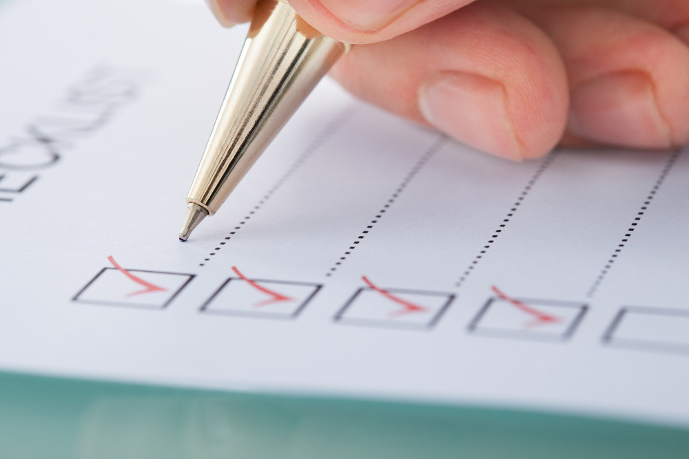 person writing on a pad with check boxes ticked