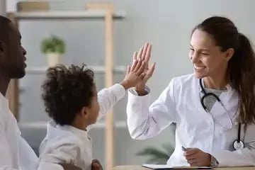 child and medical professional high fiving