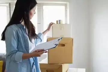 Woman with checklist and packing boxes