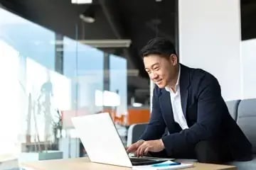 asian man in suit working on laptop