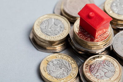 monopoly house on a pile of pound coins