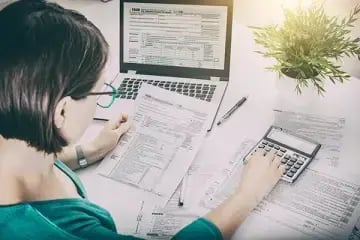 woman with glasses with laptop and calculator